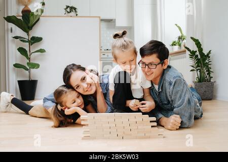 Young family playing together, building toy wall from wooden blocks Stock Photo