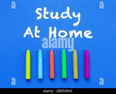 Study at home. Words or typed text on blue board. Colorful crayons. Top view. Education concept. Stock Photo