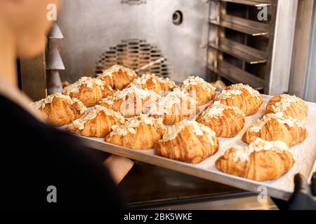 Young adult woman holding tray with gold and crispy croissants Stock Photo
