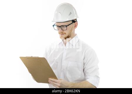 Handsome architector in hard hat makes notes on clipboard on white background Stock Photo