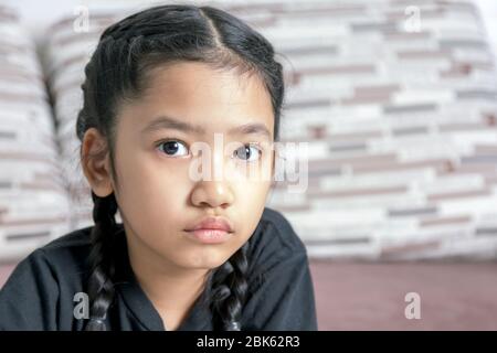 Close-up A little Asian girl in a black braid on the sofa Stock Photo