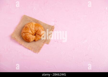 Top view croissant on the brown sack. Bread on the pink background and texture. Stock Photo