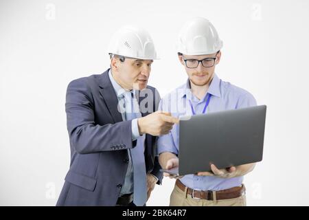 Two engineers in hard hats discuss new project while using laptop Stock Photo