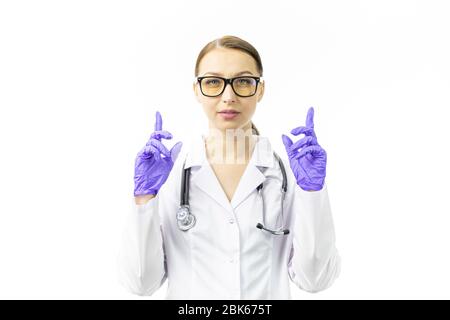 young female doctor looks at camera pointing her index fingers up in blue gloves Stock Photo