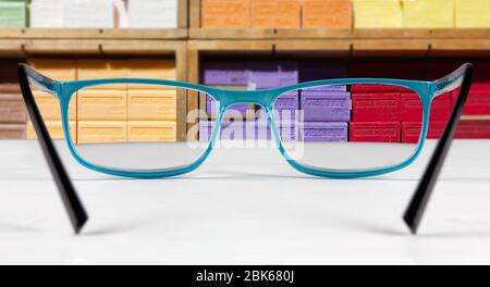 Display of Marseille soaps in different fragrancies seen through a pair of eyeglasses lying on a white table Stock Photo