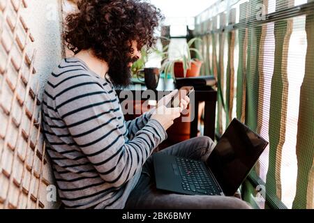 Young afro caucasian with laptop in his balcony Stock Photo