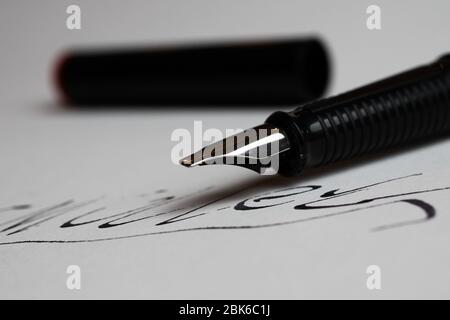 Contract conclusion concept: Macro close up of isolated black ink pen and handwritten signature on white paper (focus on tip of pencil) Stock Photo