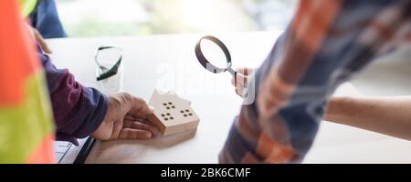 real estate and inspector concept, looking house model by magnifying glass in construction site table Stock Photo