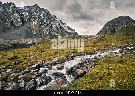 Dramatic scenery of foggy mountains and river in Altyn Arashan George, Kyrgyzstan Stock Photo