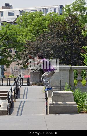 In the shadow of the elevated subway a young man practices Parkour, the art of balancing on unusual obstacle courses. Stock Photo
