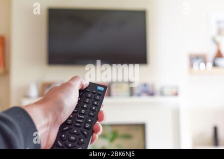 Hand with tv remote control switching television on at home Stock Photo