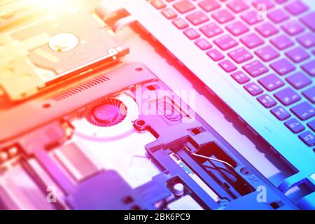 Closeup on electronic motherboard, neon light, hardware repair shop. Blurred panoramic image with opened laptop circuitry, close-up on electronics. To Stock Photo