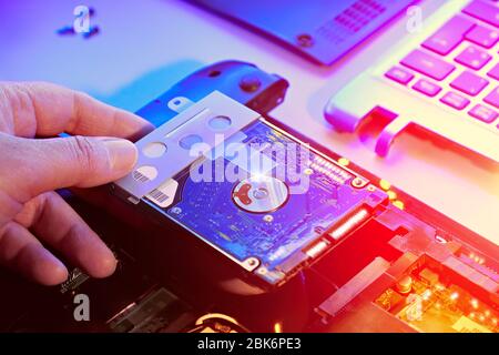 Closeup on hand with hard drive, electronic motherboard card in hardware repair shop. Blurred image with opened laptop circuitry, close-up on electron Stock Photo