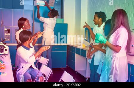 Female African medical students, young graduates or doctors discuss ongoing project. Energetic young team working in hospital test lab Testing samples Stock Photo