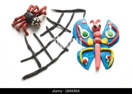 Spider caught a butterfly in its web. The scene is molded of multi-colored plasticine on white background. Stock Photo