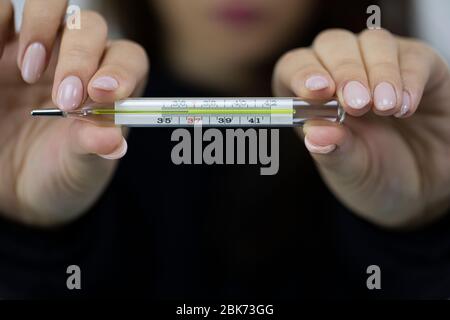 Girl holds medical glass thermometer with optimal temperature of healthy person Stock Photo