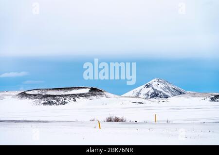 Dramatic volcanic landscape with snow covered crater near lake Myvatn, Iceland in mid winter, against a blue sky Stock Photo