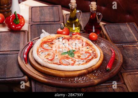 Appetizing pizza with peppers, mushrooms and ham on wooden tray Stock Photo