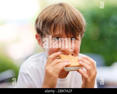 Close up portrait of beautiful, cute, little boy, holding ice cream sandwich in his hand, looking ahead Stock Photo