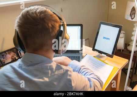 A teenaged boy has a remote lesson from his school during lockdown for Coronavirus in 2020 Stock Photo