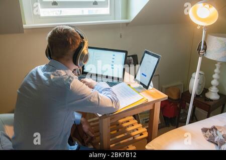 A teenaged boy has a remote lesson from his school during lockdown for Coronavirus in 2020 Stock Photo