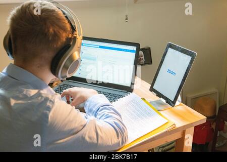 A teenaged boy has a remote lesson from his school during lockdown for Coronavirus in 2020 Stock Photo