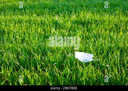medical mask lying on the green grass. Used contaminated garbage is released into the environment during the pandemic of the coronavirus covid-19. Stock Photo