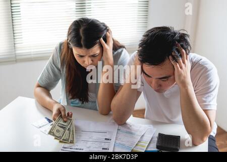 Young Asian couple felling stress, serious about financial problem of credit card debt and loan bill from shopping online Stock Photo