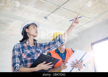 Team of Inspector holding clipboard opening paper and checking building for renovation, engineer surveyor looking in construction site. Home inspectio Stock Photo