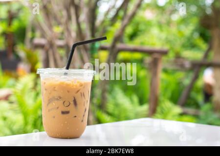 Glass of cold espresso coffee on table Background blurry views tree. Stock Photo