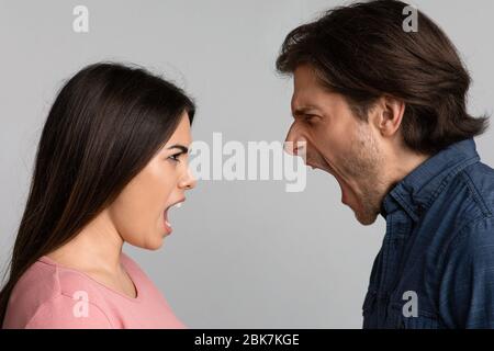 Relationship Crisis. Angry Couple Screaming At Each Other Over Light Background Stock Photo