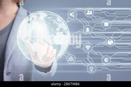 Woman in suit touching hologram of earth with diverse icons Stock Photo
