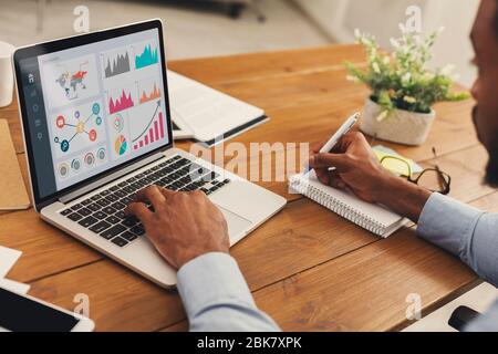 Black entrepreneur analyzing graph on laptop at workplace Stock Photo