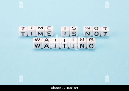 time is not waiting for you do it now - motivational phrase composed with cubes on blue background Stock Photo