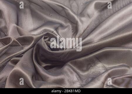 Creased beige curved cloth material fragment with swirl as fabric background texture Stock Photo