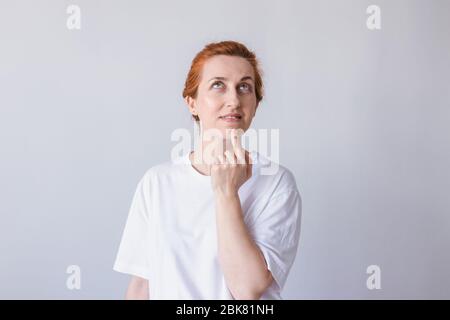 Portrait of the beautiful and cheerful young girl smiling. Loking up. White background. Stock Photo