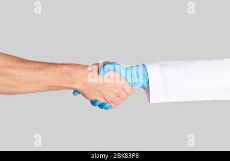 Male patient shaking hands with his doctor on light background, close up Stock Photo