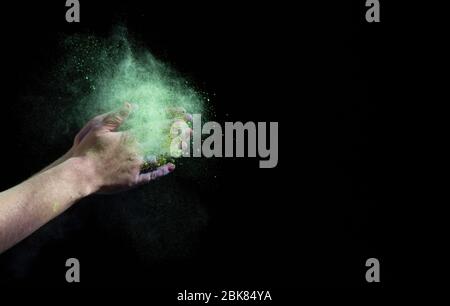 Green cloud of paint around hands on black background