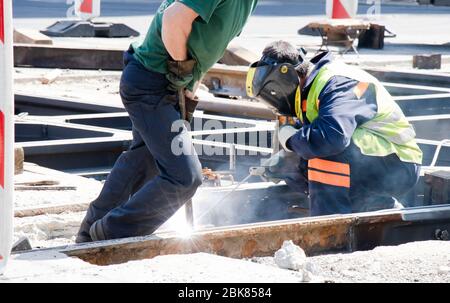 Belgrade, Serbia - April 23, 2020: Welder construction workers working on city street tram railway crossroad, repairing and replacing old rotten rails Stock Photo