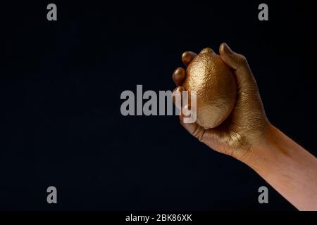 Minimalism concept. Hand holds lemon in gold paint Stock Photo