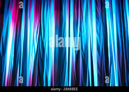 Blue and purple lit with different colours texture of a textile theatre curtain during the presentation. Texture template and mockup. Stock Photo