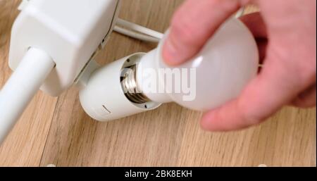 Mans Hands Replacing a Light Bulb in lamp. Close-Up. Stock Photo