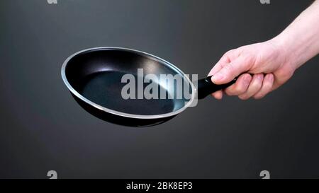 Hands holding new empty black frying pan. Close up. Stock Photo