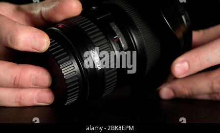 A man's hand turns the focus wheel on the lens. Close up. Stock Photo