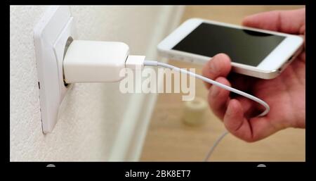 Putin white smartphone on charge. Connecting cable to the phone. Close up. Stock Photo