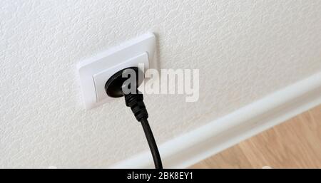 Hand Inserting black Power Plug into an white Electricity Socket. Close up. Stock Photo