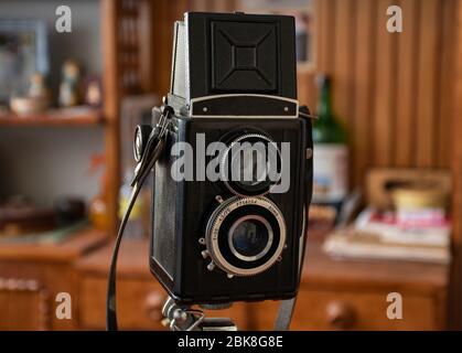 very old but in good condition twin-lens reflex antique vintage camera stays in a room, blur background Stock Photo