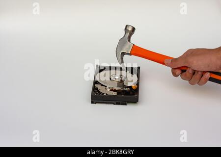 Hard disk drive platter being destroyed with a hammer on a white background. Stock Photo