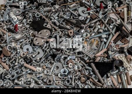 various and so many scraps, pins, screws, nuts, bolts and washers placed all together on a wooden plank Stock Photo