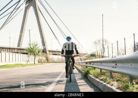 male cyclist on mountain bike in protective mask respirator in polluted city. guy ride to work on environmentally friendly transport, urban eco raffic Stock Photo